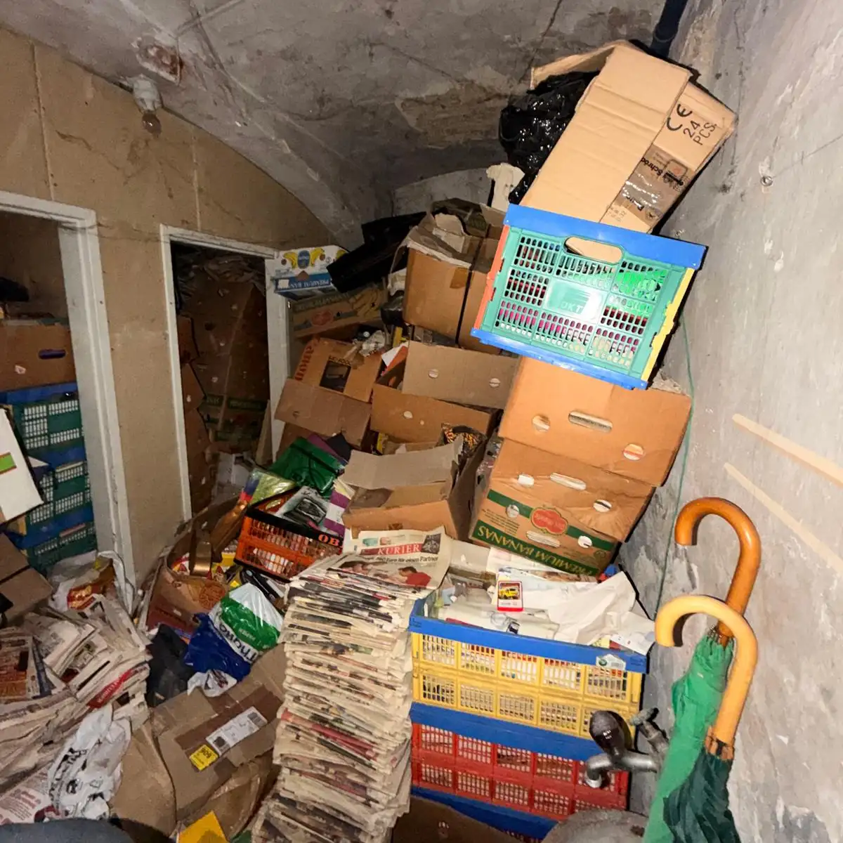 Zustand vor der Keller Räumung Wien: Stark überfüllter Keller vollgestellt mit Umzugskartons, Plastikkisten und alten Zeitungsstapeln
