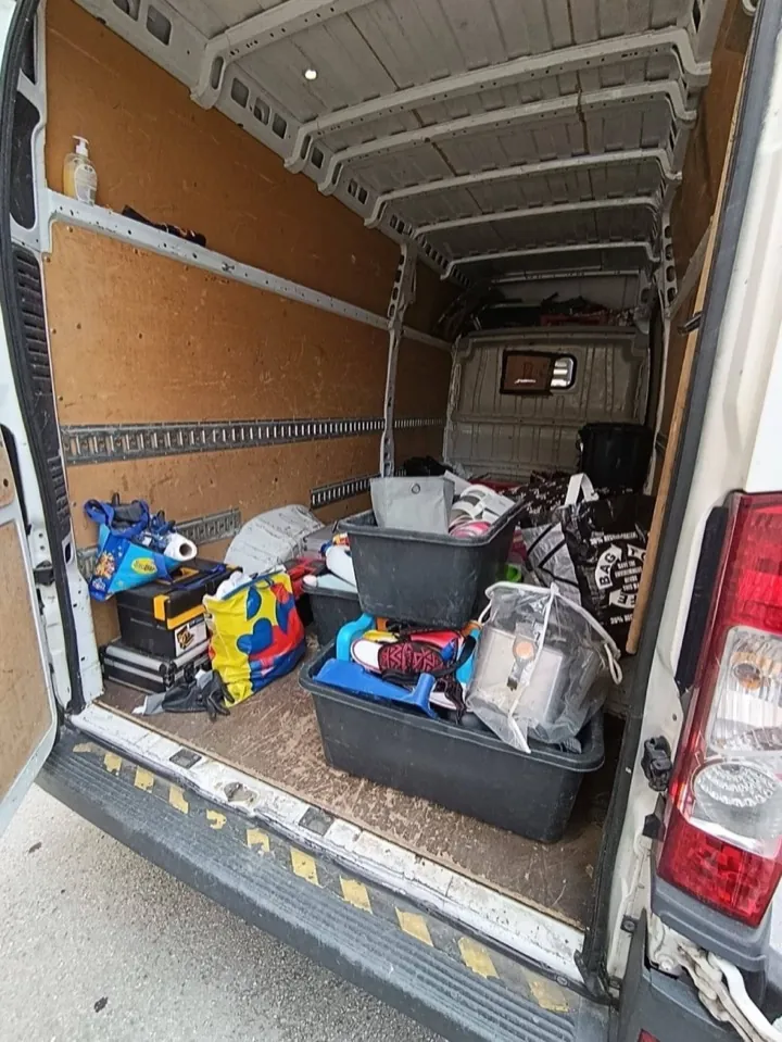 Offener Laderaum eines Kastenwagens mit Transportwannen, Kartons und Taschen, die eine Entrümpelungsfirma mitnimmt