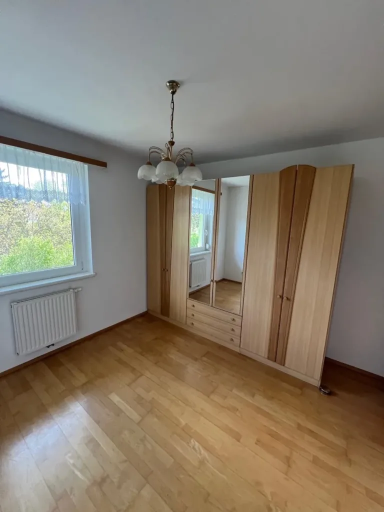 Leeres Schlafzimmer mit Parkettboden, in dem nur ein Kleiderschrank mit Spiegeltür stehen geblieben ist