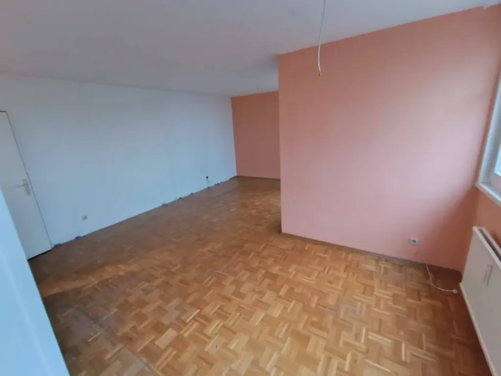 Leerer Wohnraum mit lachsfarbener Wand, Möbelabdrücken und Parkett nach einer Räumung, nicht nach einer Entrümpelung