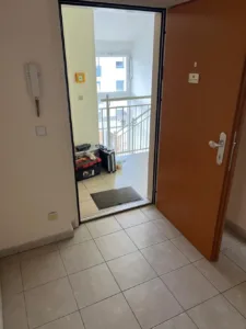 Räumung ohne Anwesenheit: offene Wohnungstür am Laubengang, dahinter leerer Vorraum mit Werkzeugkoffer und Trolley