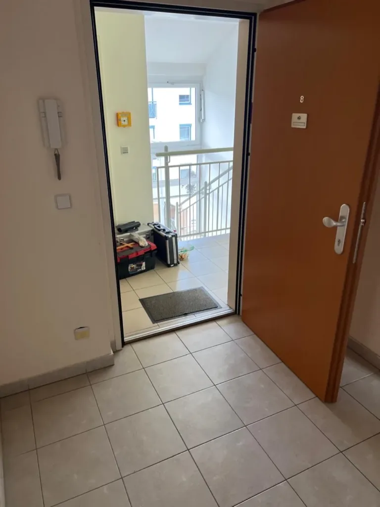 Vollzugstag nach einer Räumungsklage in Österreich: gefliester Vorraum, offene Wohnungstür, Werkzeugkoffer am Laubengang